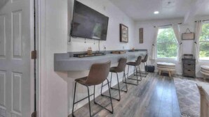 Cozinha moderna com área de bar, banquetas e uma grande televisão de tela plana.