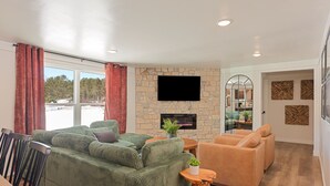 A living room with a green sofa, a tan sofa, a wooden coffee table, and a stone fireplace. - Big Yard Hot Tub Fire Pit Trail Pictured Rocks (Munising)