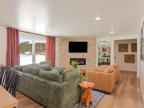A living room with a green sofa, a tan sofa, a wooden coffee table, and a stone fireplace.