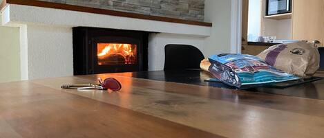 A wooden table with a fireplace, a clock, and a bag of chips.