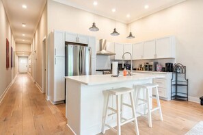 A modern kitchen with white cabinetry, stainless steel appliances, and a central island with bar stools.