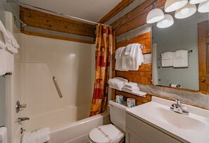 Un baño con bañera, inodoro, lavabo y techo de madera.