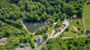 Vue aérienne d’un quartier résidentiel avec des maisons, un étang central et de la végétation environnante.