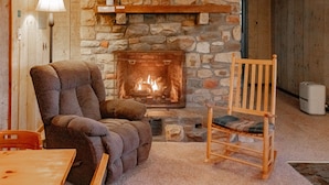 Une pièce chaleureuse avec une cheminée en pierre, un fauteuil moelleux et une chaise en bois.