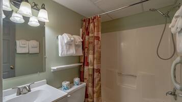 Une salle de bain avec deux lavabos, des toilettes, une douche et un miroir avec éclairage.