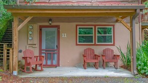 A building with a porch, two rocking chairs, a door with a number, and two windows.
