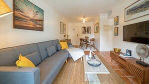A living room with a grey sofa, yellow pillows, a coffee table, and a TV. - Comfy 1b getaway w/ BEACH ACCESS & full amenities (Key Biscayne)