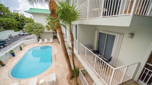 A pool area with a clear blue pool, white lounge chairs, and a palm tree. - Comfy 1b getaway w/ BEACH ACCESS & full amenities (Key Biscayne)