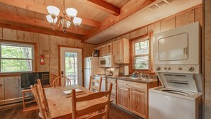 A wooden cabin kitchen with a dining table, chairs, a refrigerator, a microwave, a stove, and a television. - Cozy Lakeside Cabin #15 - Sleeps 6 - Full kitchen + fireplace - between Boone & Blowing Rock NC (Blowing Rock)