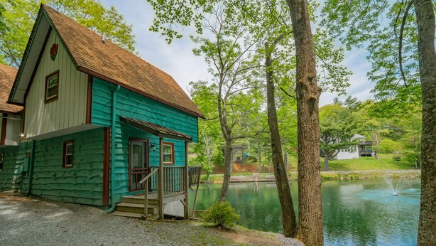 A two-story house with a porch and a pond in the background. - Cozy Lakeside Cabin #15 - Sleeps 6 - Full kitchen + fireplace - between Boone & Blowing Rock NC (Blowing Rock)
