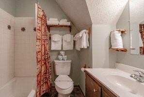 Ein Badezimmer mit Duschvorhang, Toilette, Waschbecken und Handtuchhaltern.