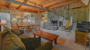 Un salon chaleureux avec une cheminée, un coin repas et une cuisine.