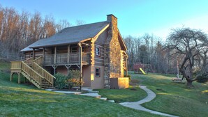A log cabin with a stone chimney, a wooden deck, and a staircase leading to a balcony. - Cozy Cabin #5 - Sleeps 6 - Full kitchen + fireplace - between Boone & Blowing Rock NC (Blowing Rock)