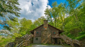 A rustic lodge with a stone chimney, wooden exterior, and a gravel driveway.