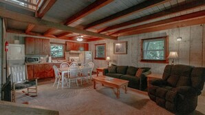 Interior acolhedor de uma cabana com área de jantar, um sofá e uma cozinha.