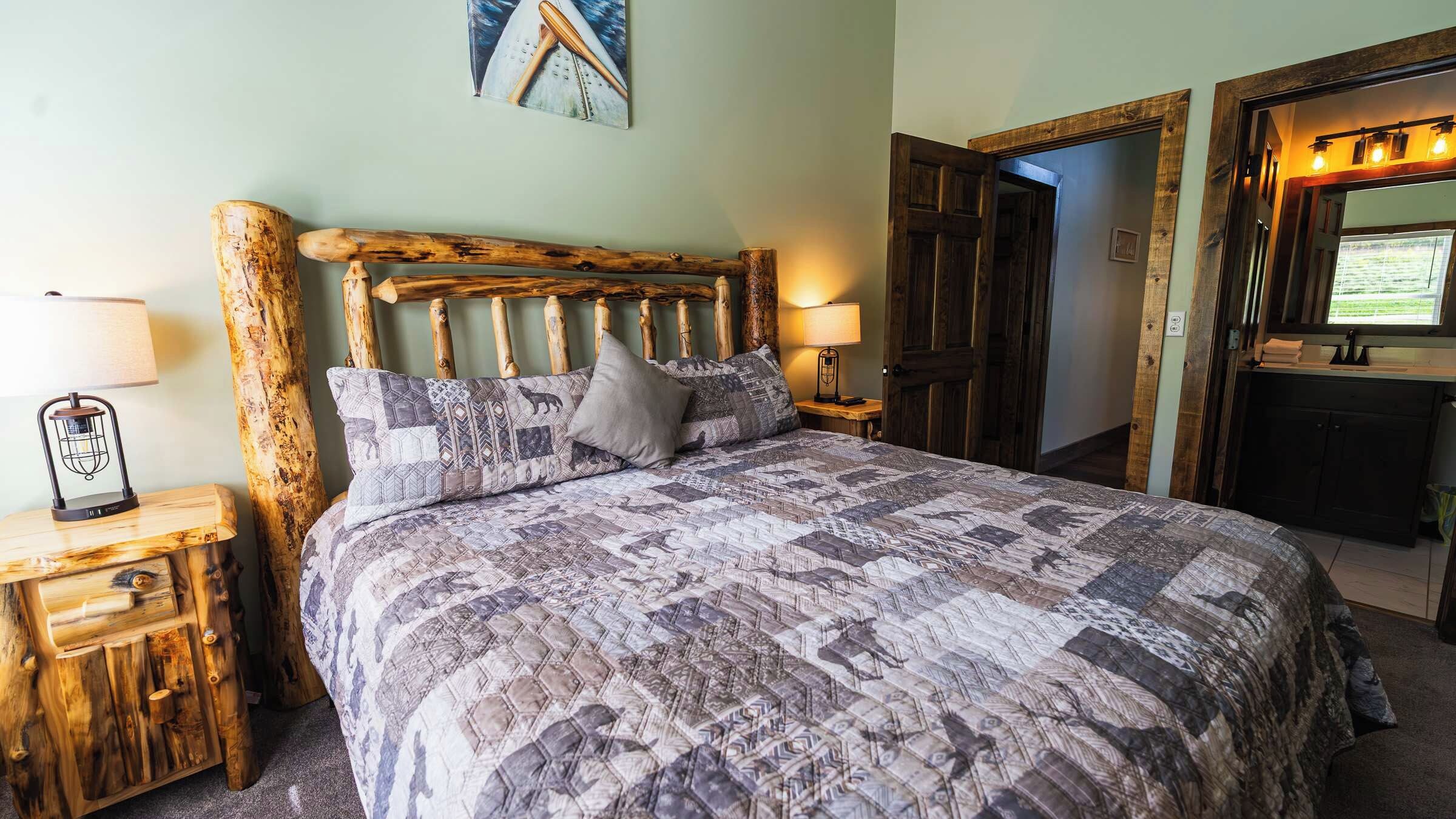 A bed with a patterned quilt, two bedside lamps, and a wooden headboard.