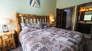 Uma cama com um edredom estampado, duas luminárias de cabeceira e uma cabeceira de madeira.