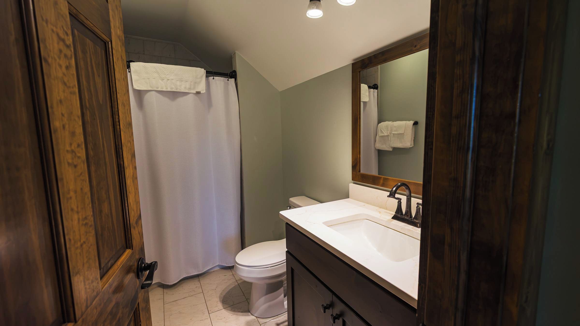 Une salle de bain équipée de toilettes, d’un lavabo, d’un miroir et d’un rideau de douche.