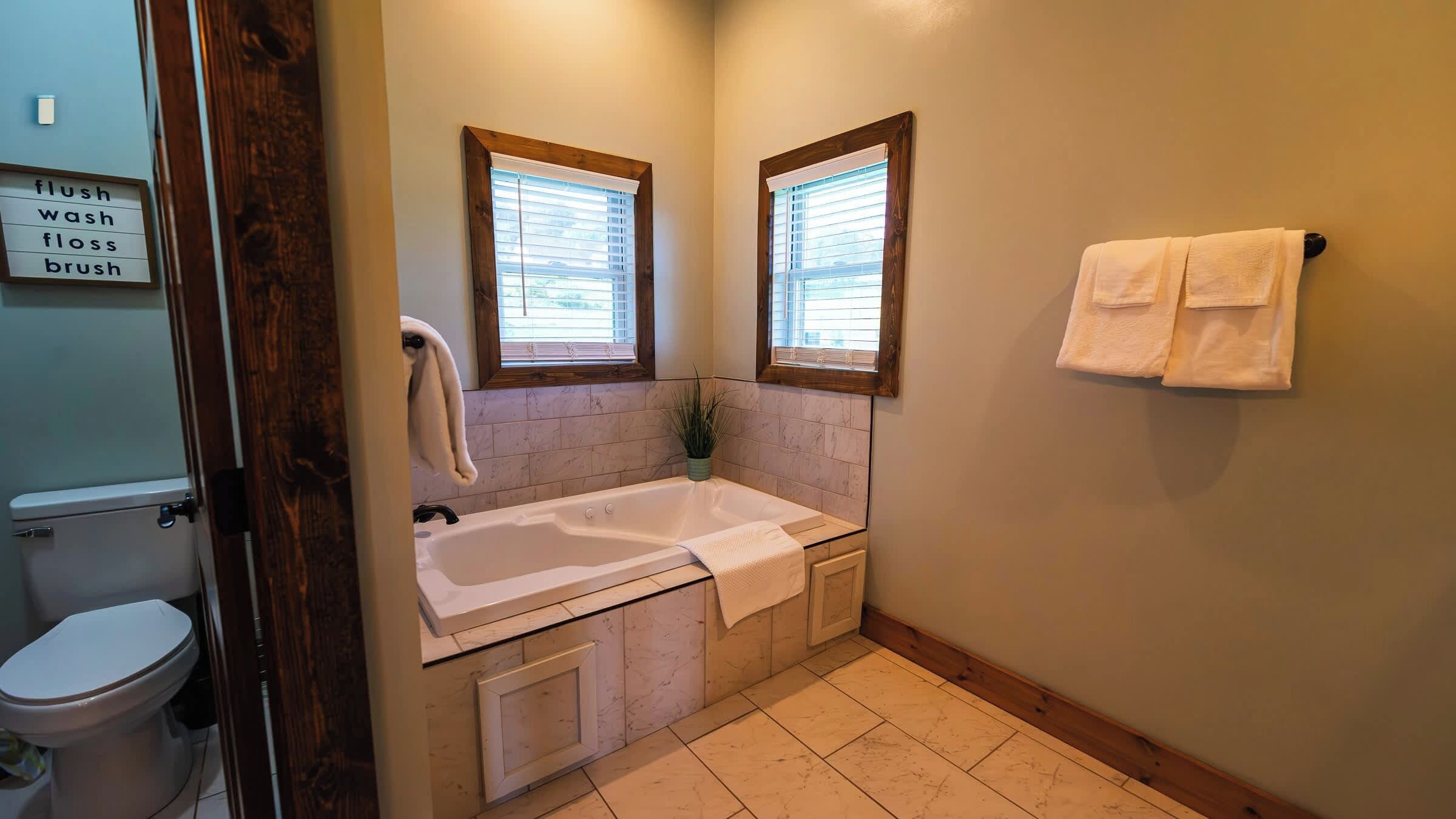 A bathroom with a bathtub, toilet, and a towel rack.