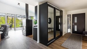 A modern interior with a sliding glass door leading to a balcony, a black-framed sliding door, and a wooden floor. - Villa Eslahti - Seafront/Jacuzzi (Porvoo)