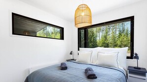 A modern bedroom with a large bed, two windows, and a hanging light fixture. - Villa Eslahti - Seafront/Jacuzzi (Porvoo)