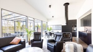A modern living room with a fireplace, large windows, and a dining area. - Villa Eslahti - Seafront/Jacuzzi (Porvoo)