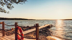 A wooden pier extending into calm water, with a lifebuoy attached to the railing. - State of the Art Coastal Villa (Salo)