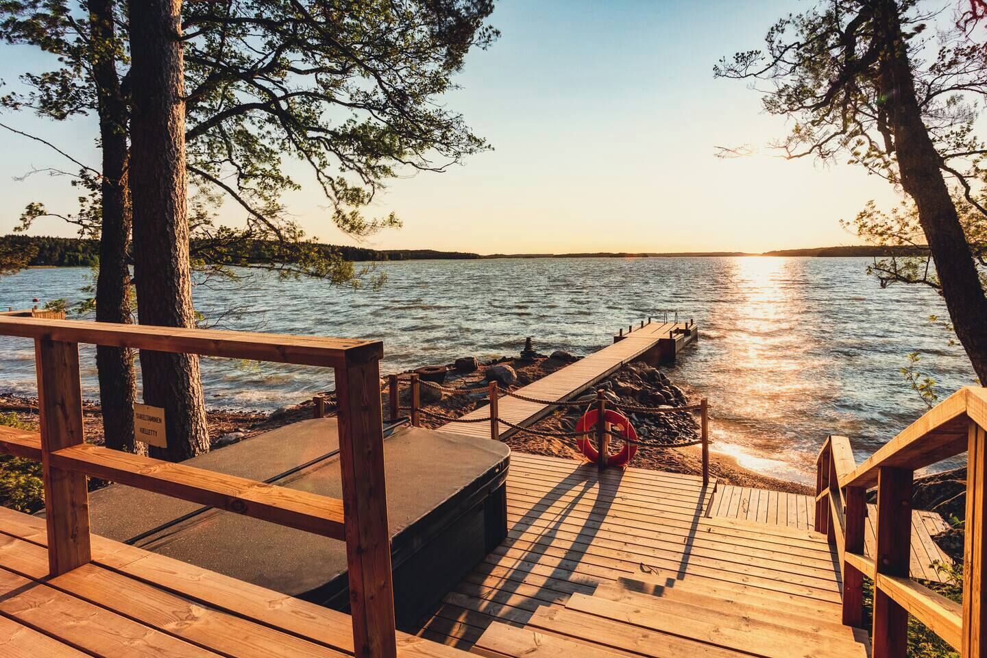 A wooden deck with a lifebuoy, a wooden bench, and a sign that reads "DIREKTIMMEN KELLETTY".