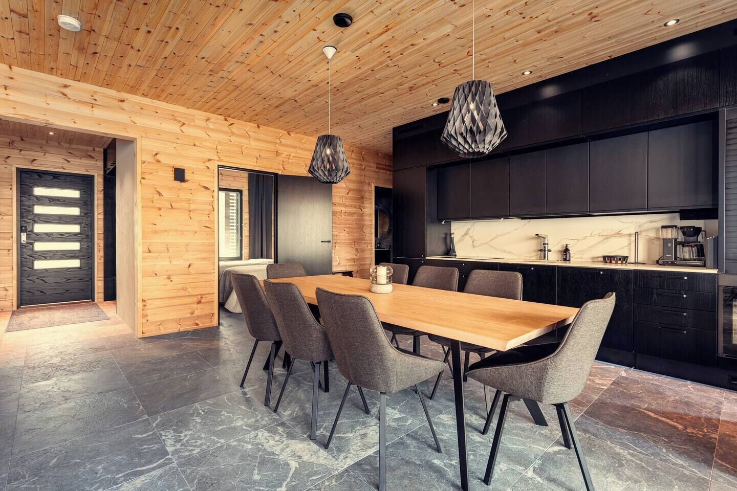 A modern kitchen with dark cabinets, a marble countertop, and a built-in oven.