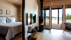 Un dormitorio con cama, televisor, chimenea y vistas al exterior.