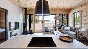 Un interior moderno con una amplia mesa central, una chimenea, un sofá y un televisor.