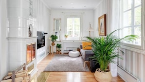 A spacious living room with a fireplace, large windows, and a cozy rug.
