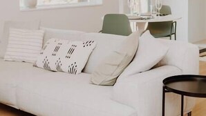 A modern living room with a white sofa, a dining table with chairs, and a black side table. - Red Mtn Private Mountain Escape for Active Couples (Rossland)