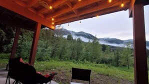 A covered outdoor seating area with chairs and a view of a mountainous landscape. - Red Mtn Private Mountain Escape for Active Couples (Rossland)