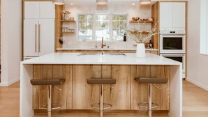 Een moderne keuken met een centraal eiland, houten details en hanglampen.