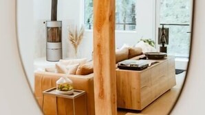 Een moderne woonkamer met een grote houten balk, een bank, een salontafel en een open haard.