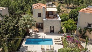 A two-story house with a swimming pool, outdoor furniture, and a garden.