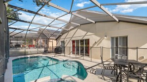 Piscina descoberta coberta com área de terraço, incluindo uma mesa e cadeiras, e vista para o bairro ao redor.