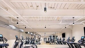 A gym with multiple treadmills and exercise bikes, a polished floor, and a high ceiling with visible ductwork. - Mid Century Modern Apartment w/ a pool! (Judson)