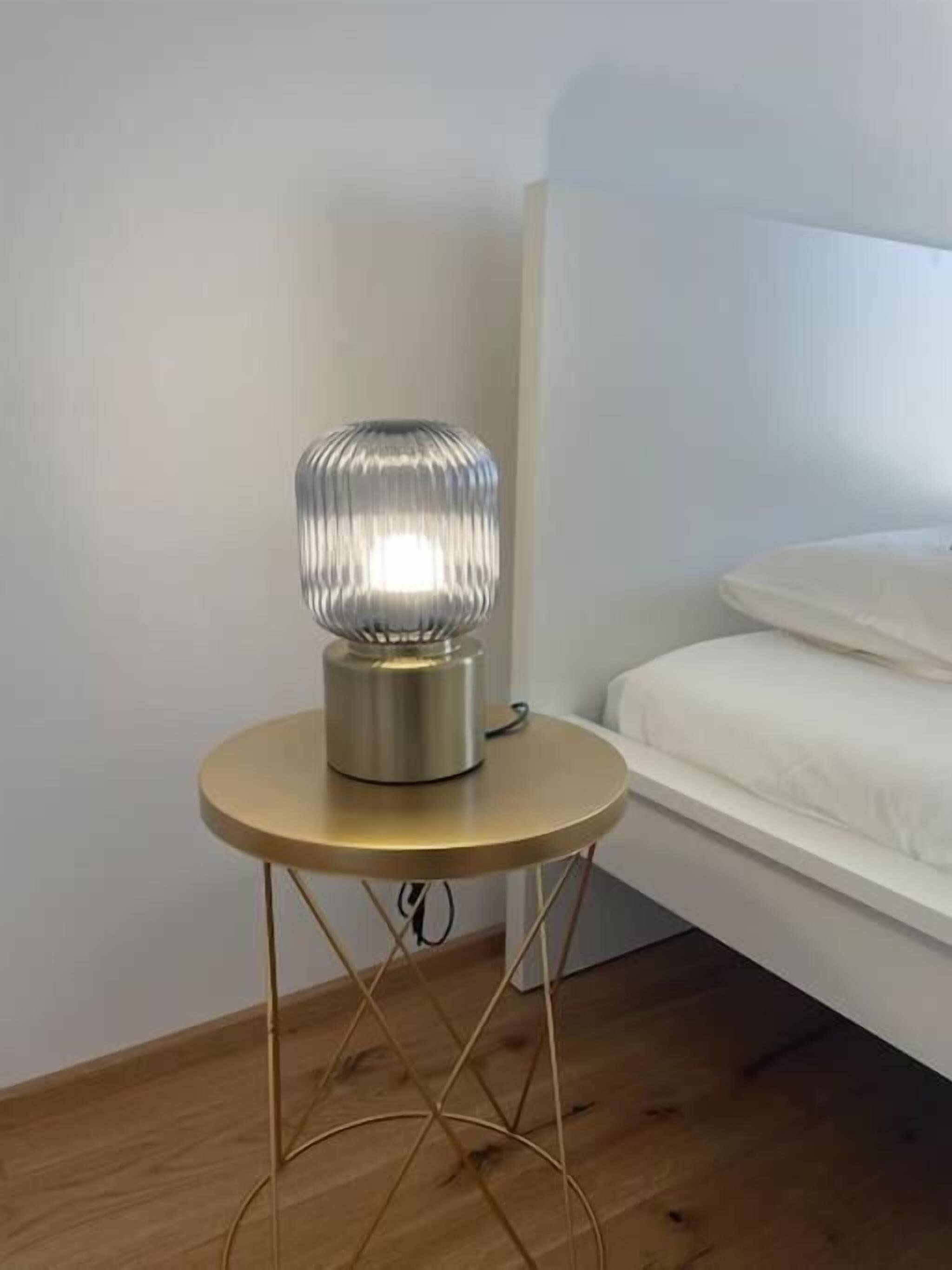Moderni huone, jossa on pyöreä pöytä, metallinen lamppu ja valkoinen sänky.
