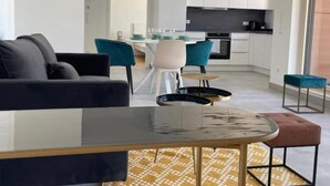 Un salon moderne comprenant un canapé, une table basse en verre et un coin repas avec des chaises et une table.