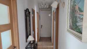 A hallway with wooden doors, a mirror, a table with a lamp, and a painting on the wall.