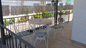 A covered outdoor patio with a round table and white metal chairs.