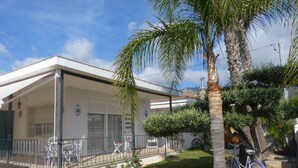 A single-story house with a covered porch, a bicycle, and a palm tree.