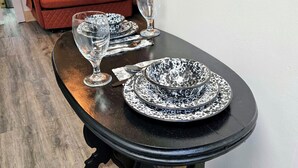 Una mesa de comedor con mantel negro, un plato blanco con diseño moteado negro, una copa de vino transparente y un tazón blanco con diseño moteado negro.