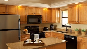 A kitchen with wooden cabinets, a stainless steel refrigerator, a black microwave, a stove, and a dishwasher.
