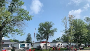 A lakeside campsite with cabins, a sandy beach, and a yellow inflatable raft.
