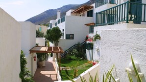 A courtyard with white buildings, green railings, and a small garden. - Apartment with Sea View, Kalimera Village (Hersonissos)