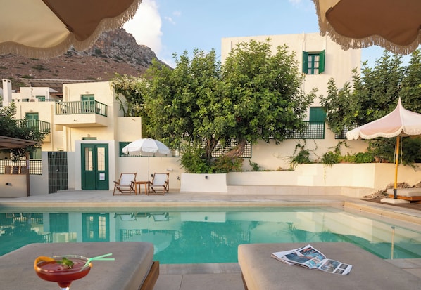 Un espace aménagé au bord de la piscine, avec des chaises longues, une boisson et un magazine.