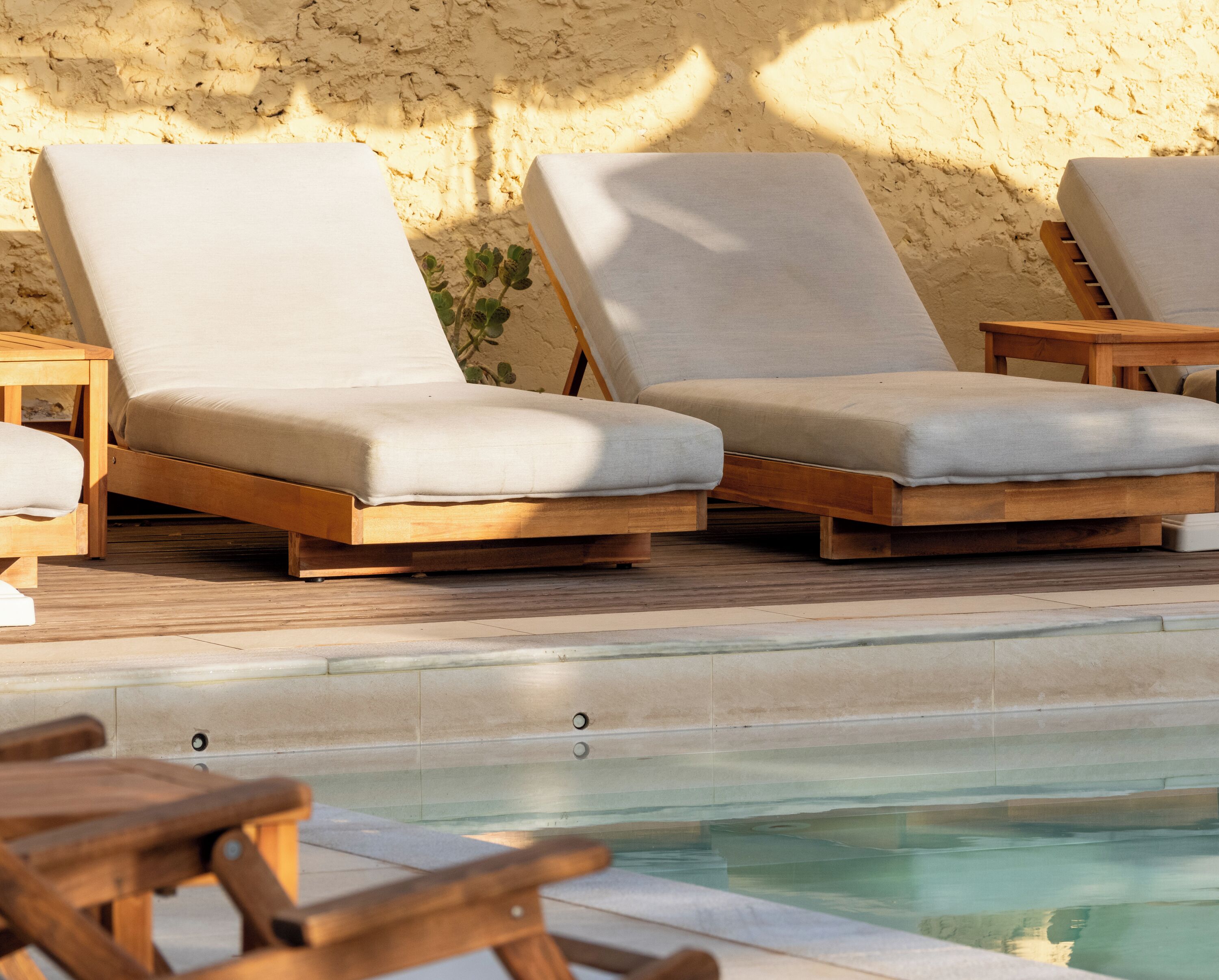 Ein Poolbereich mit Holzliegen und einer gefliesten Terrasse.
